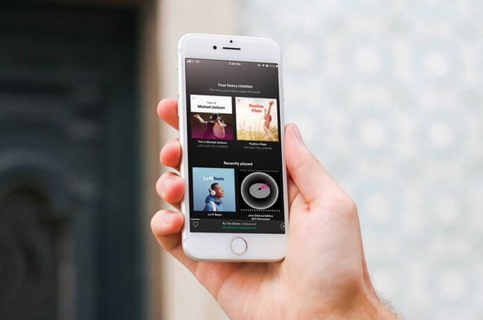 Seseorang memegang smartphone yang sedang membuka aplikasi Spotify